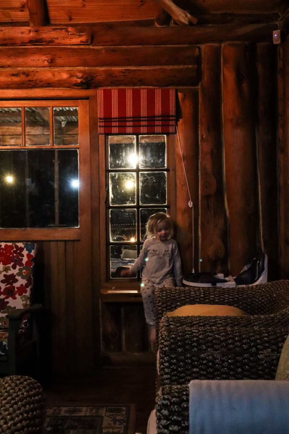 Evening inside the log cabin, lamplight through cottage windows